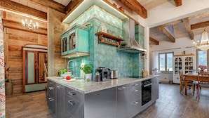 Una cocina con una isla central, vigas de madera y ventana con vista a un paisaje nevado.