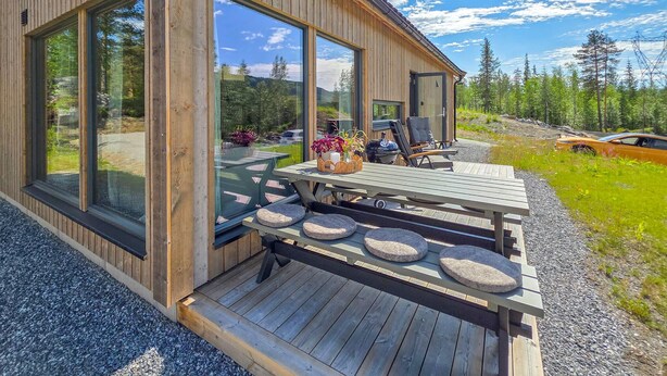 A wooden cabin with large windows, a deck with seating, and a grill. - Amazing home in Gol with house a mountain view (Gol)
