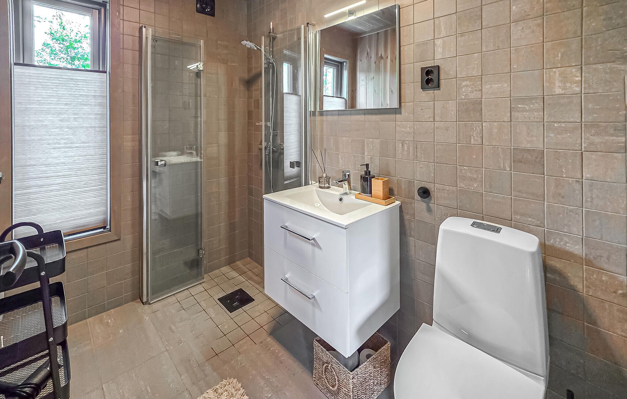 Een badkamer met douche, wastafel en toilet.