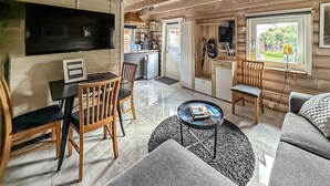 Un accogliente interno di una baita con zona pranzo, soggiorno con divano, televisione e angolo cottura.