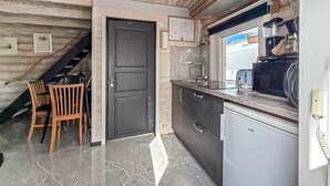 Una cucina con una porta scura, un piccolo frigorifero e una finestra vista mare.