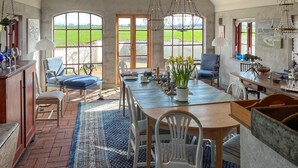 Uma sala de jantar espaçosa com uma mesa grande, cadeiras e vista para o campo.