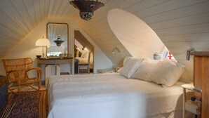 Quarto com uma cama grande, uma cadeira, uma escrivaninha e um espelho.