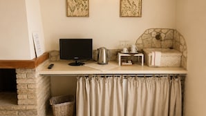Een gezellig hoekje met een stenen openhaard, een flatscreen televisie, een stenen muur en een klein tafeltje met een waterkoker en kopjes.