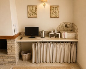 A cozy corner with a stone fireplace, a flat-screen TV, a stone wall, and a small table with a kettle and cups.