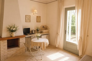 Une pièce chaleureuse avec une cheminée, une table à manger, un téléviseur et une porte donnant sur un jardin.