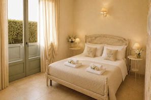 A bedroom with a bed, two bedside tables with lamps, a window with curtains, and a door.