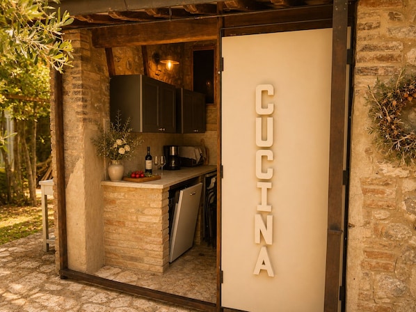 A kitchen with a stone wall, wooden cabinets, and a 'CUCINA' sign.