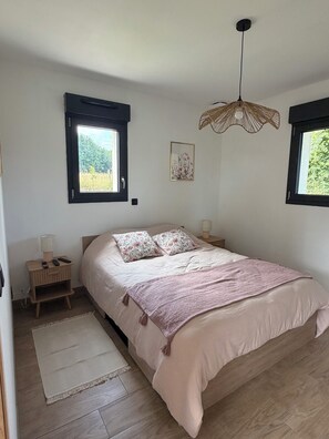 A bedroom with a large bed, two bedside tables, a hanging light fixture, and two windows. - Ô p'tit Normand: A peaceful, green spot near Honfleur (Genneville)