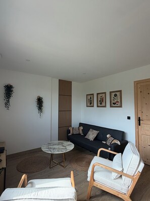 A modern living room with a sofa, two chairs, a coffee table, and decorative wall art. - Ô p'tit Normand: A peaceful, green spot near Honfleur (Genneville)