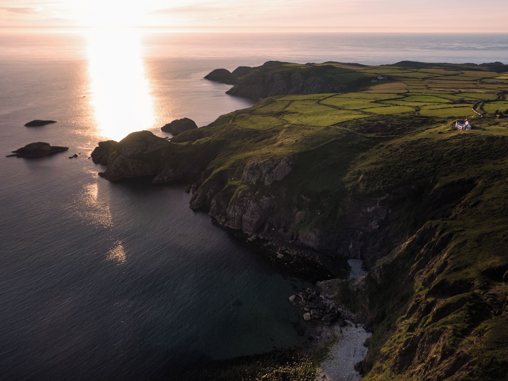 Un paysage côtier avec des falaises, une étendue d’eau et une petite maison située sur le versant d’une colline.
