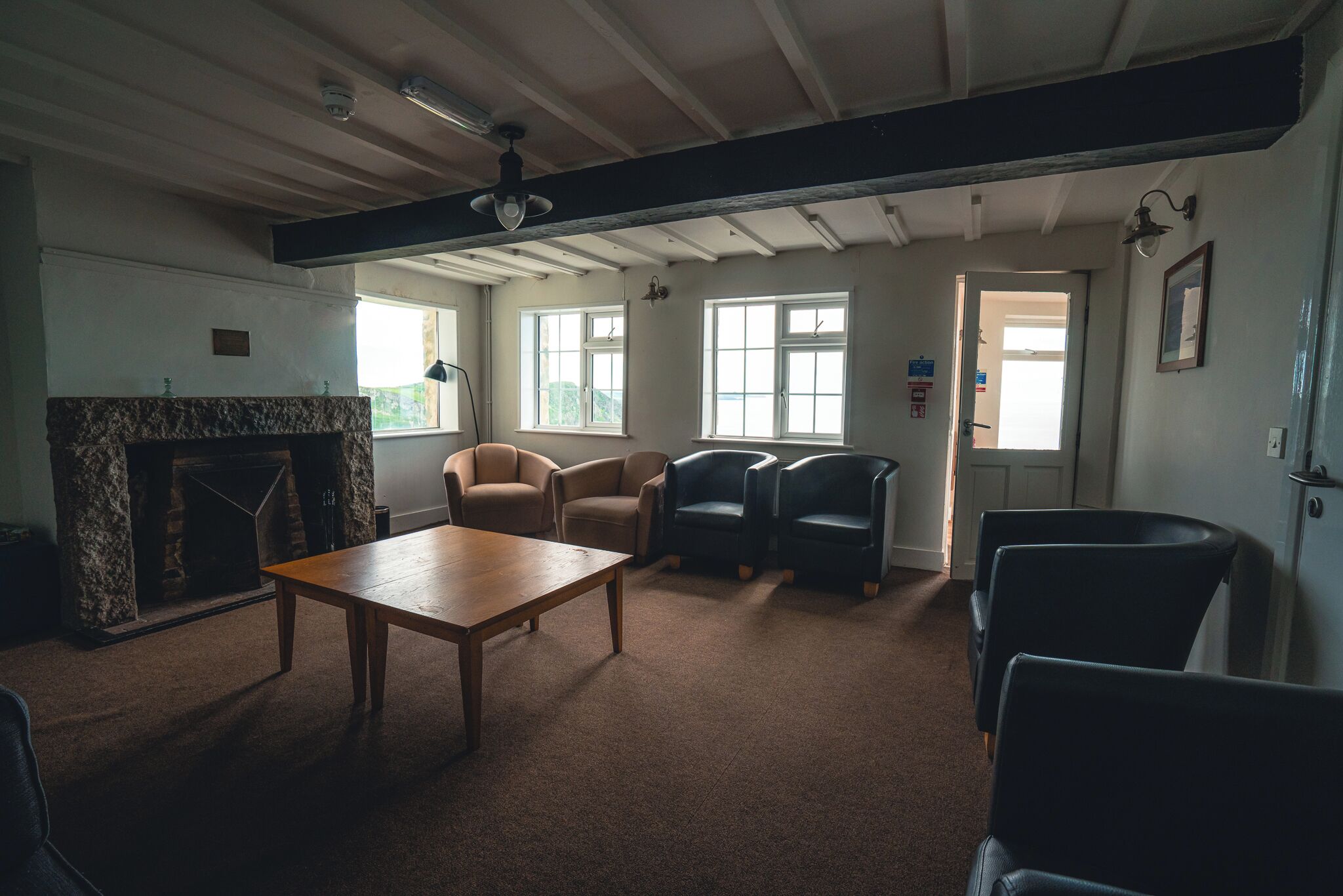 A spacious room with a fireplace, multiple seating options, and large windows providing natural light.