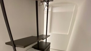A narrow room with a built-in bench and shelves, a white pillow, and a window.
