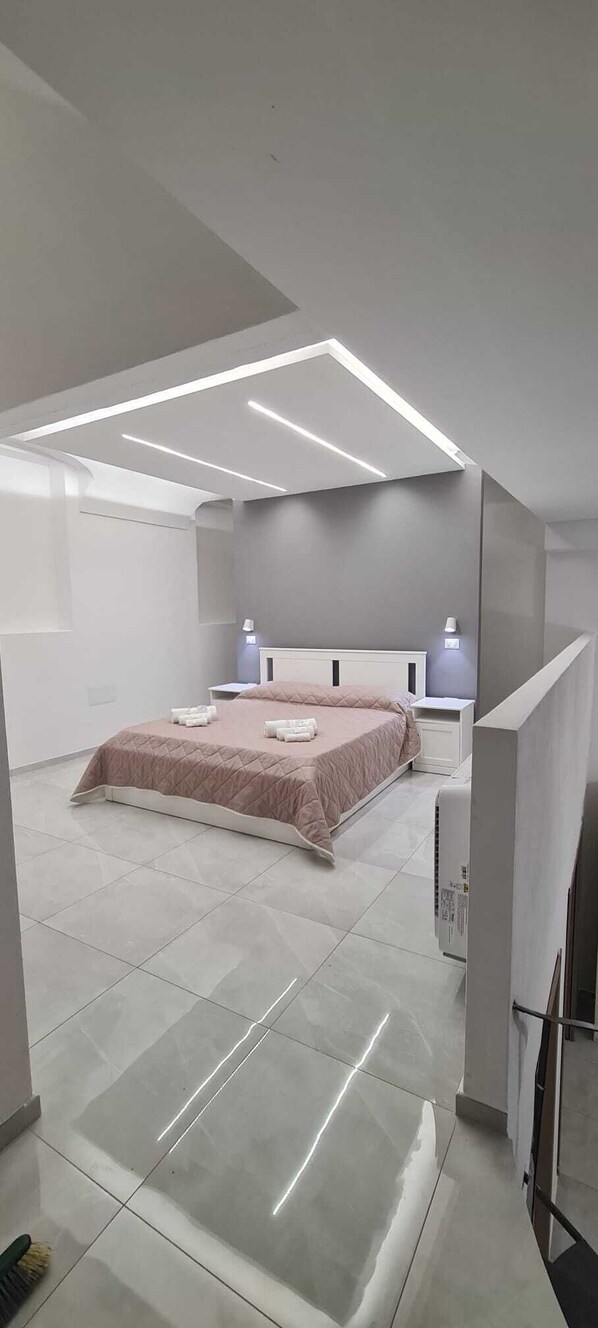 Une chambre à coucher moderne avec un grand lit, des tables de chevet et un luminaire au plafond.