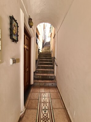 A narrow hallway with a tiled floor leading to a staircase. - La Terrazza - Cozy Room in the Center of Capri (Capri)