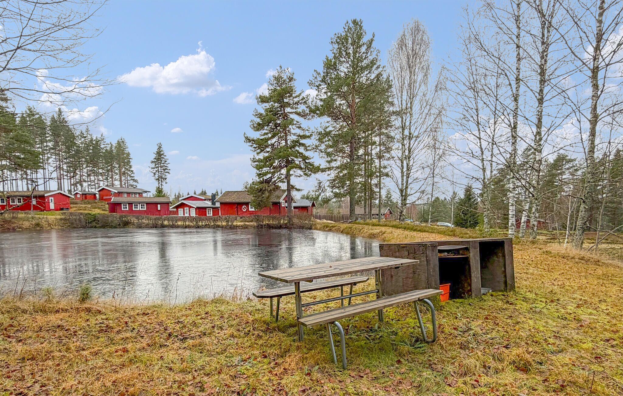 A lakeside cabin area with a picnic table and a small shelter.
