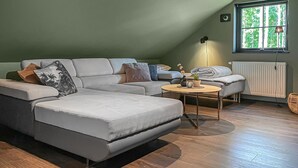 Et moderne loftrum med en krogsofa, et rundt bord og en radiator.