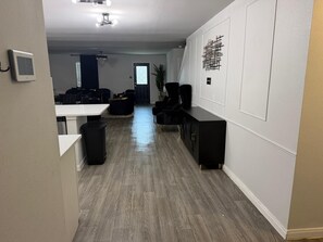 A modern living room with a wooden floor, a black sofa set, a coffee table, and a TV on a stand. - The Grand Haven 5BR 3BTR Family Retreat Sleeps 12. Spacious and Stylish (Cleveland)