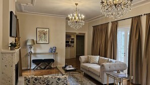 A living room with a sofa, a coffee table, a chandelier, and a bookshelf. - Balnagowan, Garden Retreat 3-Bed Home in Moss Vale (Moss Vale)