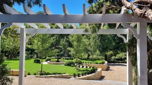 A garden with a white pergola, a circular stone fountain, and neatly trimmed hedges. - Balnagowan, Garden Retreat 3-Bed Home in Moss Vale (Moss Vale)