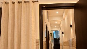 Um corredor de hotel com chão de azulejos, escada e plantas em vasos.