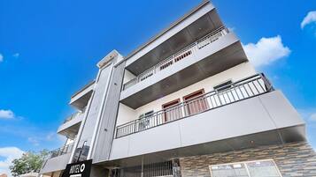 A multi-story hotel with balconies, a sign indicating 2 company suites, and a modern architectural design.