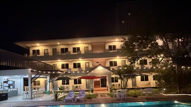 A swimming pool with a tiled surface, surrounded by outdoor seating and a building with multiple windows and balconies. - Amaya Bloom Resort & Spa (Pattaya)