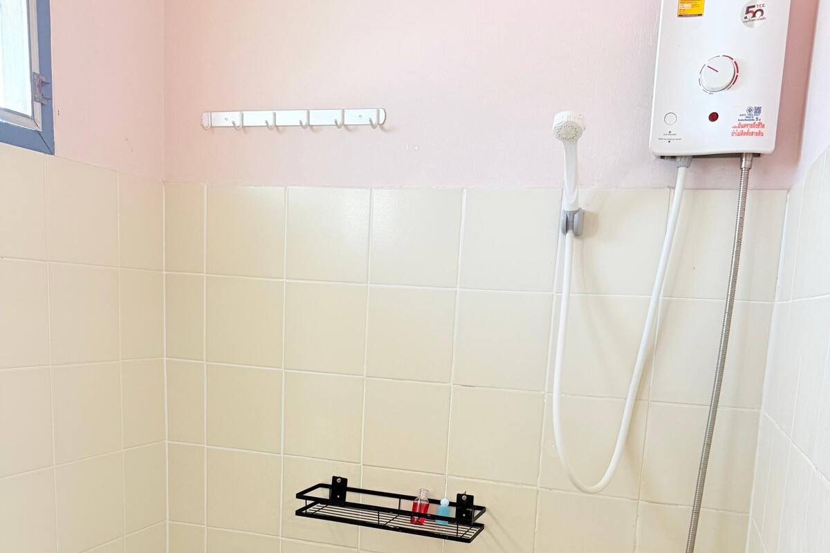 Un baño pequeño con inodoro, ducha y estante con artículos de aseo.