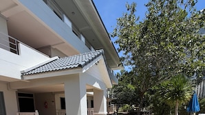 A building with a covered entrance, a paved pathway, and a well-maintained lawn. - Amaya Bloom Resort & Spa (Pattaya)