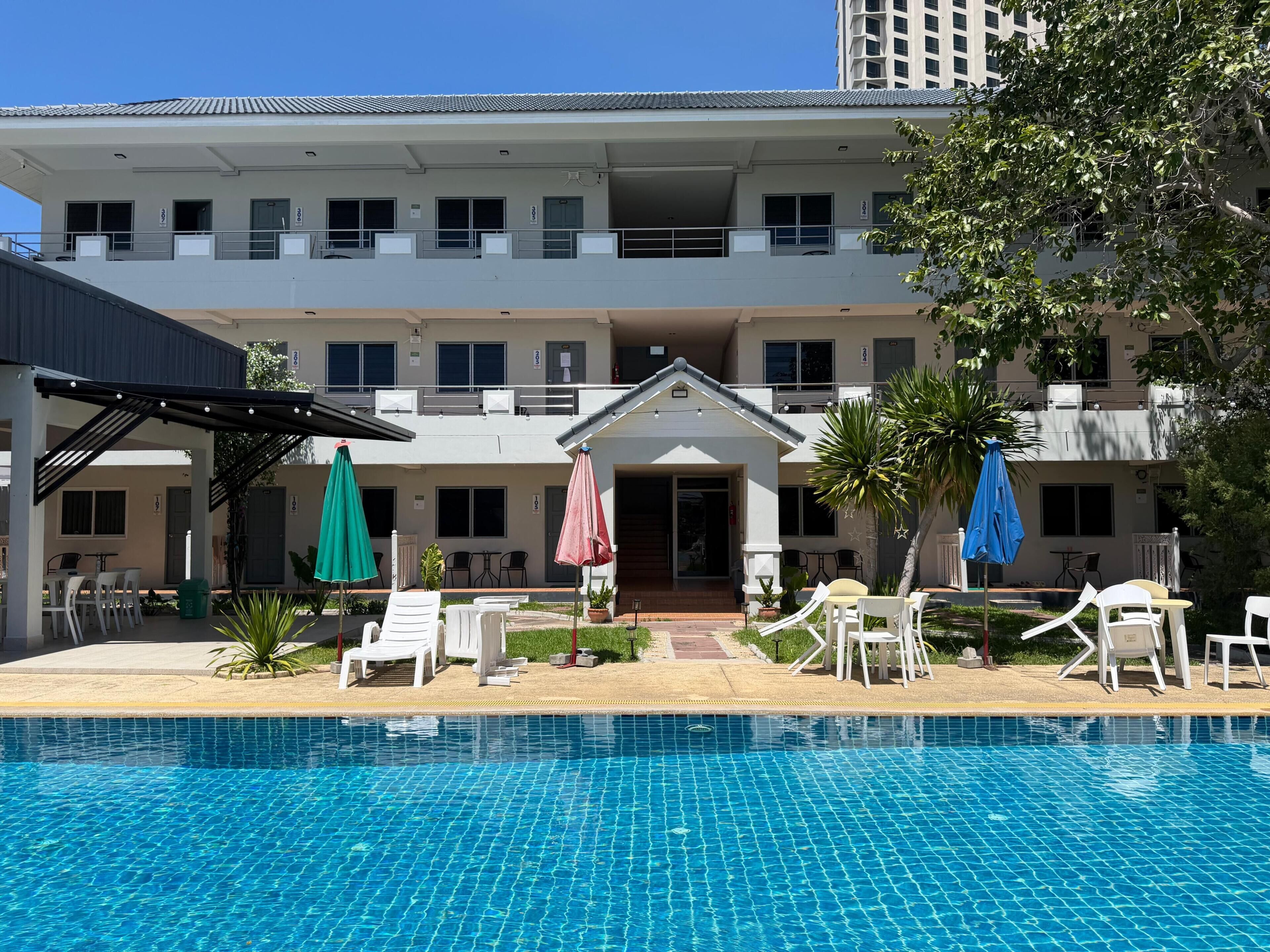 Un hotel con piscina, mobiliario exterior y un patio cubierto.