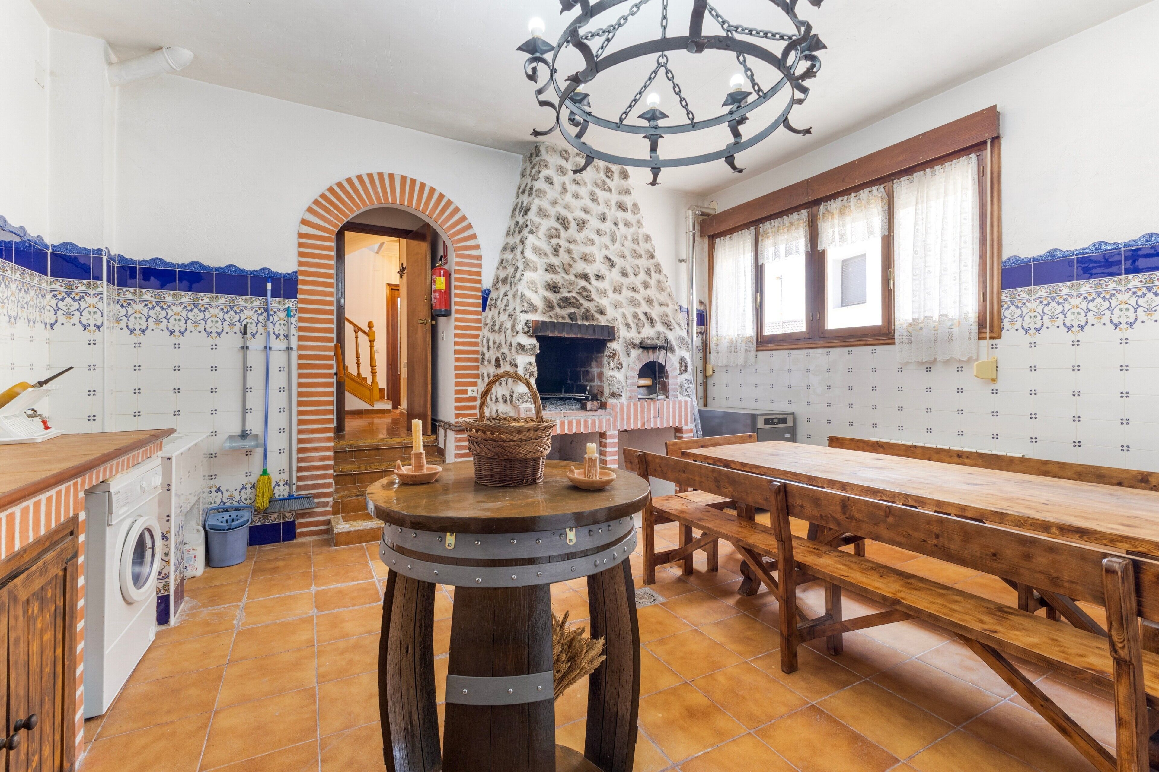 Une cuisine avec un four en pierre, une table en bois et un lave-linge.