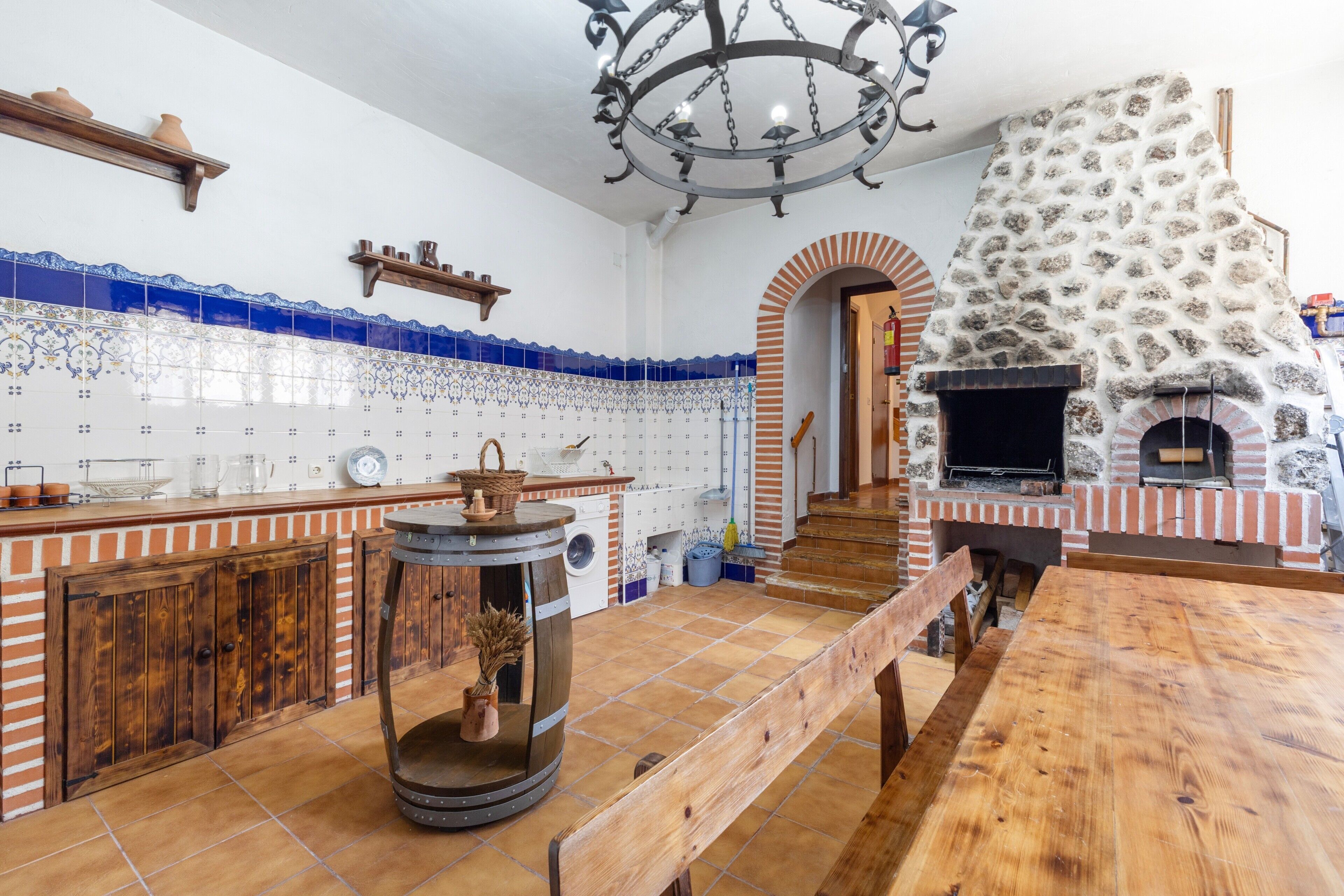 Une cuisine avec un four en pierre, des meubles en bois et des carreaux bleus et blancs.
