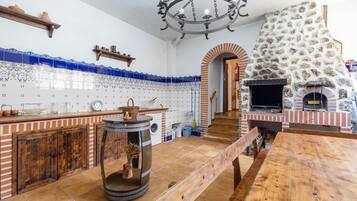 Une cuisine avec un four en pierre, des meubles en bois et des carreaux bleus et blancs.