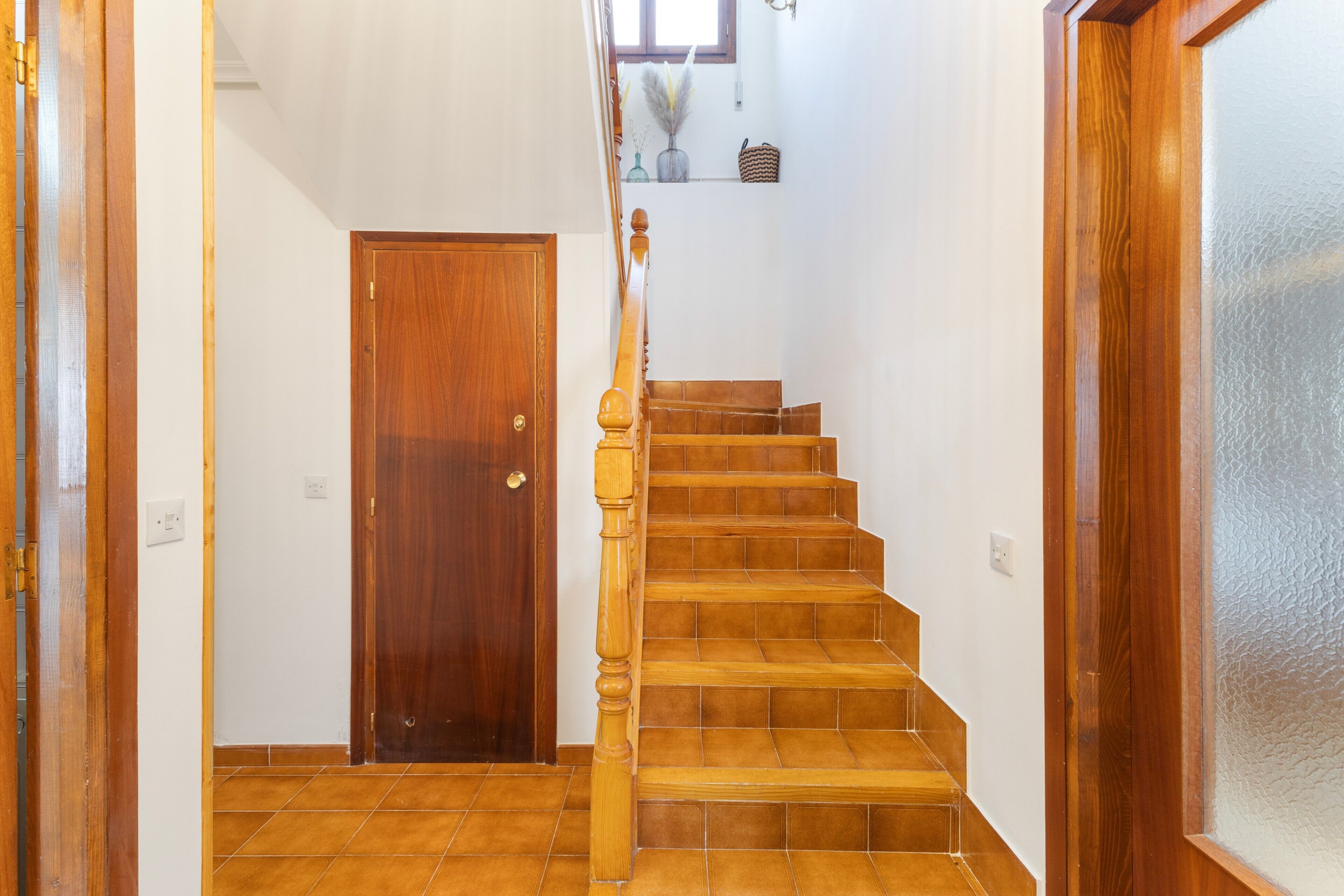 A wooden staircase with a handrail leading to a landing.