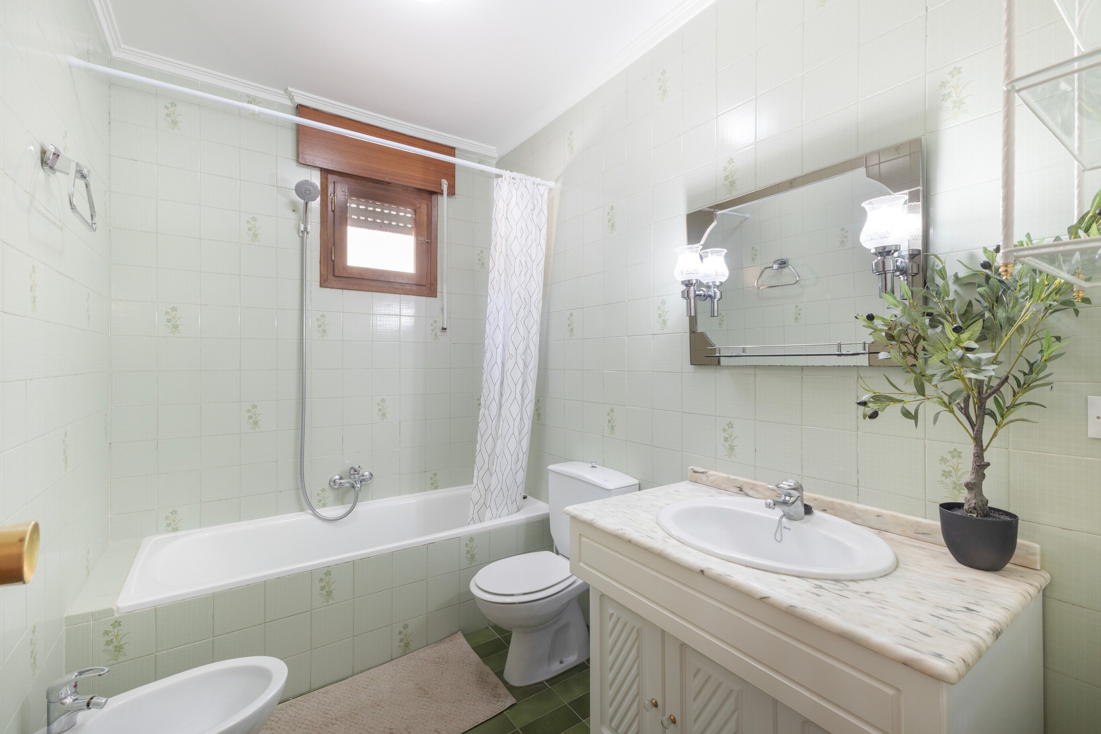 A bathroom with a bathtub, toilet, sink, and a mirror.