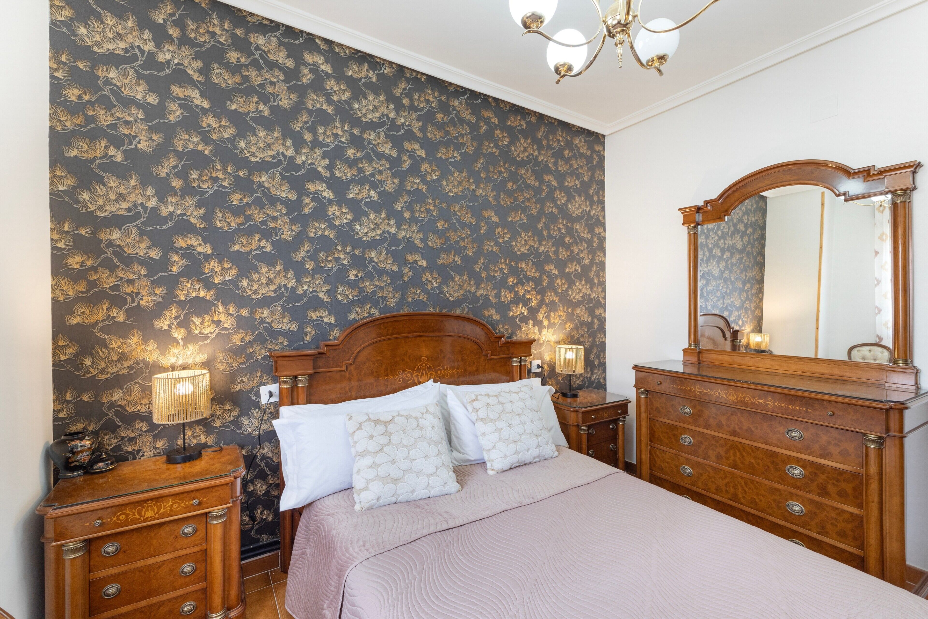 Een slaapkamer met een bed, twee nachtkastjes, een dressoir en een spiegel.