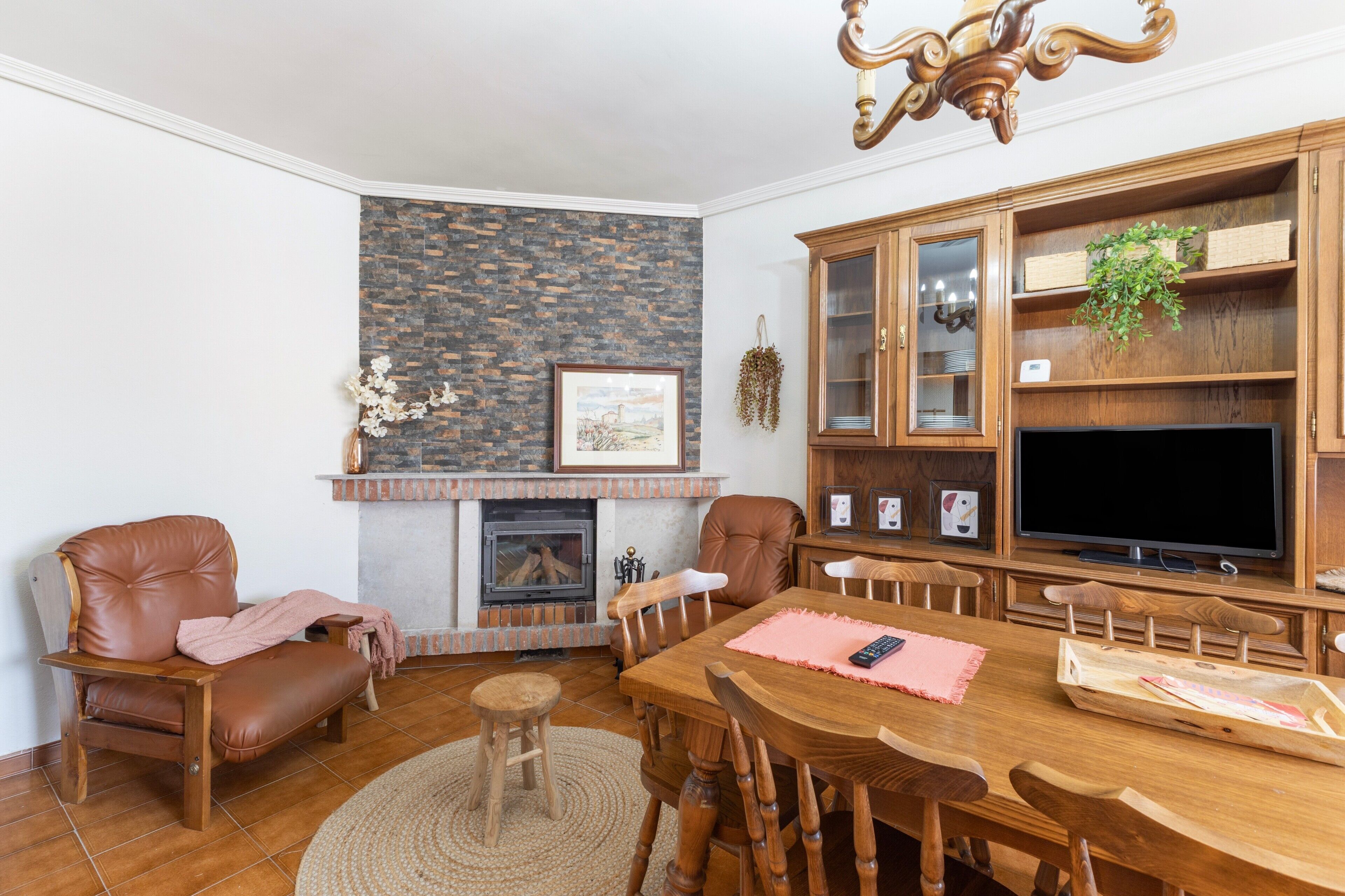 Un salon avec une cheminée, un téléviseur, des meubles en bois et un mur d’accent en pierre.