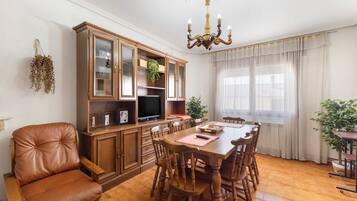 A dining area with a wooden table, chairs, a cabinet, and a television.