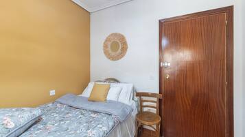 Un dormitorio con una cama, una puerta de madera y un adorno en la pared.