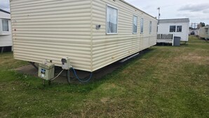 Una casa móvil con techo plano, entrada lateral y un pequeño porche.
