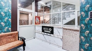 A hotel reception area with a marble counter, a bench, and a staircase visible through the windows. - Classic With Balcony Shri Hari Palace Guest (Mathura)