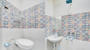 A bathroom with a white toilet, a sink, and a shower. The walls are decorated with colorful geometric tiles. - Classic With Balcony Shri Hari Palace Guest (Mathura)