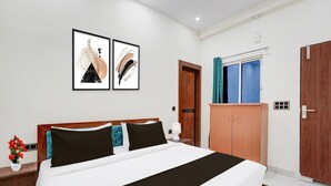 A hotel room with a bed, wooden wardrobe, a door, and a window with curtains. - Classic With Balcony Shri Hari Palace Guest (Mathura)