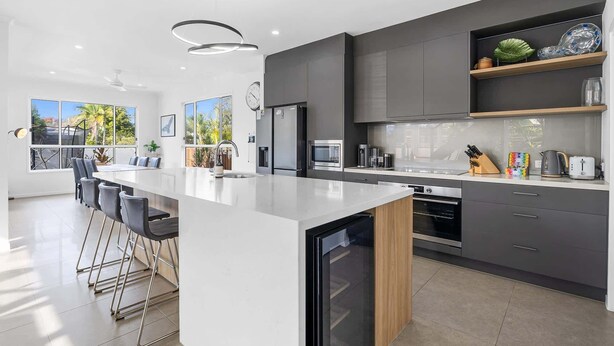 Una cocina moderna con una isla central, electrodomésticos de acero inoxidable y vistas al exterior.