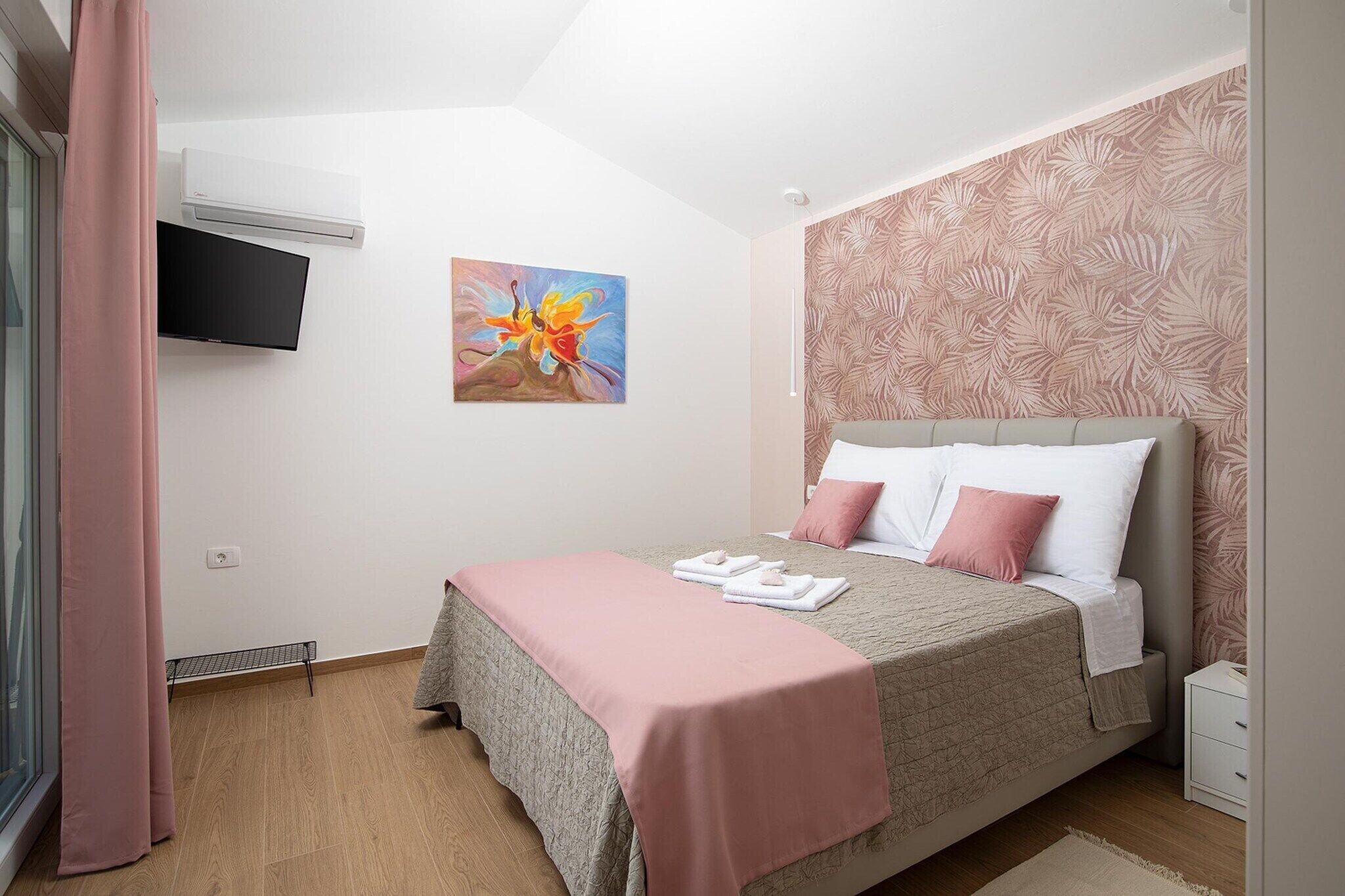 Ein Schlafzimmer mit einem Bett, einem Flachbildfernseher, einem Gemälde und einer Wand mit Muster.
