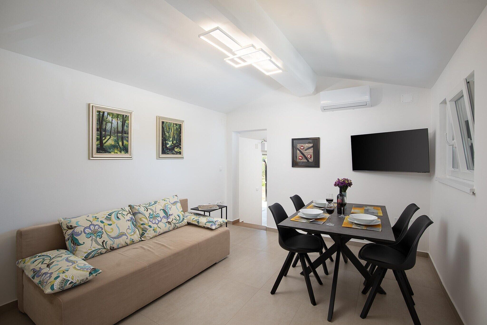 Ein modernes Wohnzimmer mit einer Couch, einem Esstisch, Stühlen und Kunstwerken an den Wänden.