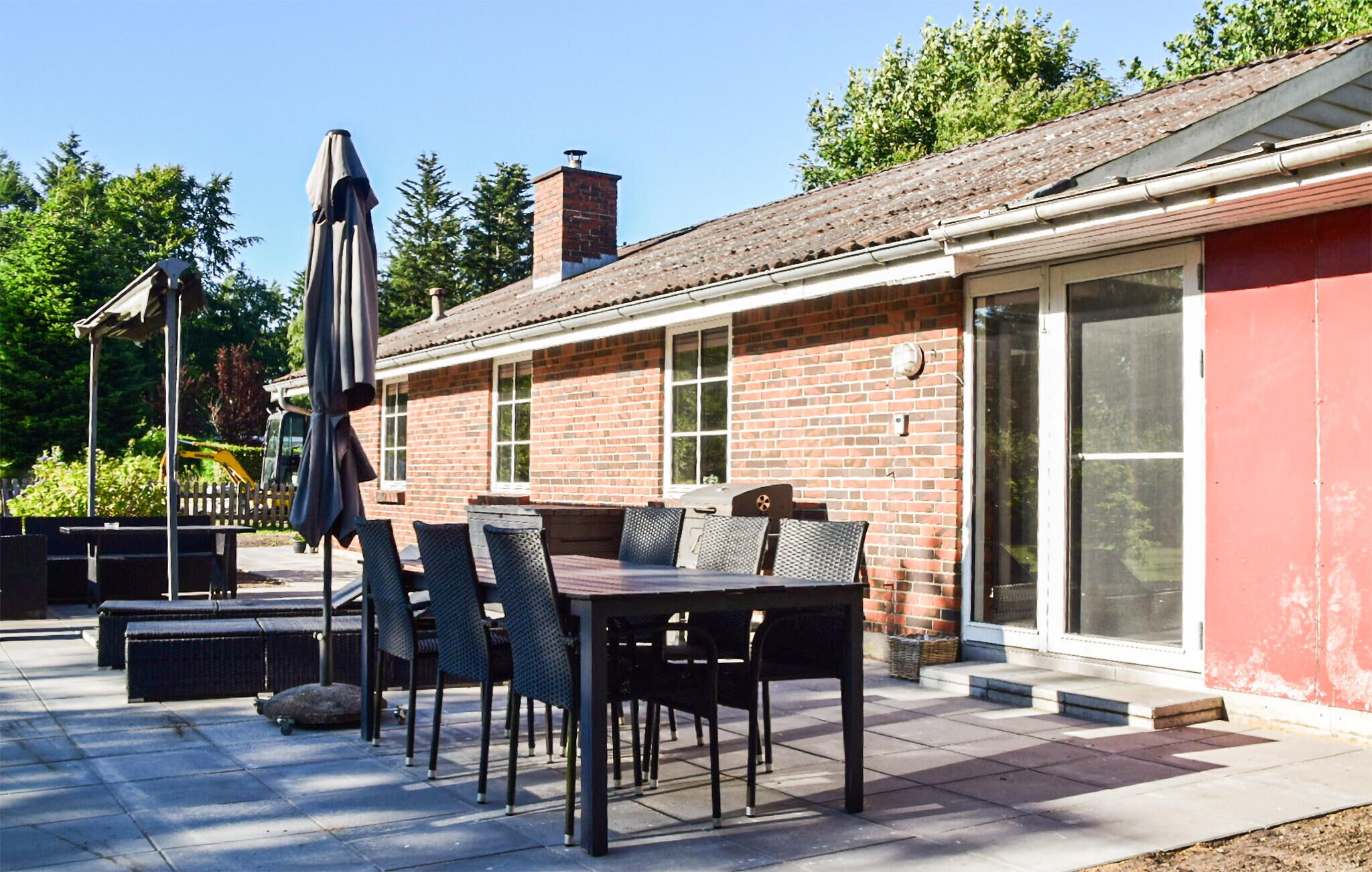 An outdoor patio with a brick building, a table with chairs, and a covered umbrella.