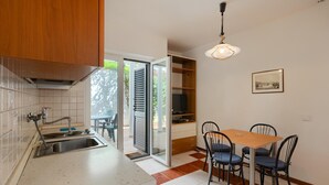 Una cocina con pileta, armarios y un comedor con sillas y una mesa.