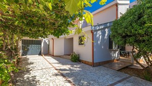 Um pátio com piso de azulejos, área de estar coberta e um edifício com garagem.