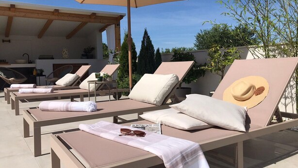 Un espace de détente aménagé sur le toit, avec des chaises longues, une pergola et une vue sur la verdure environnante.